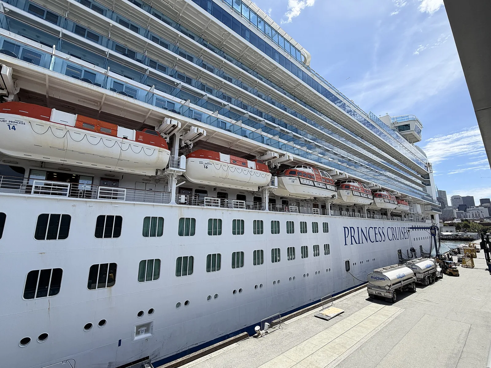 Rows of stateroom balconies stacked along the side of Ruby Princess under a bright blue sky