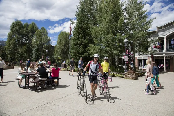 Visitors walking bicycles through Blue River Plaza in downtown Breckenridge in summer