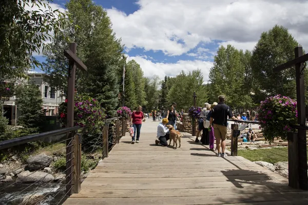 A wooden boardwalk among green trees at Blue River Plaza, Breckenridge