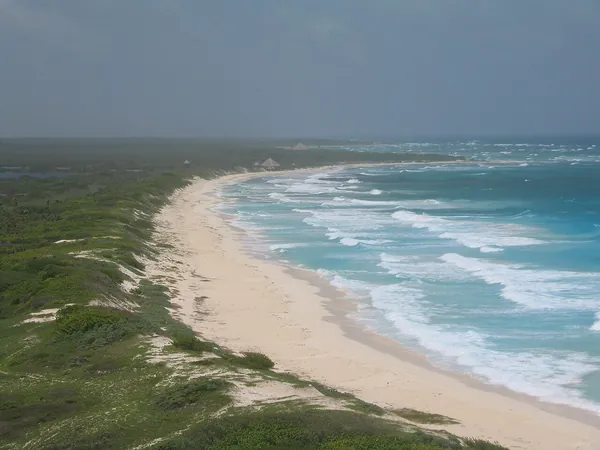 A long sandy beach and turquoise surf seen from the lighthouse on Cozumel, Mexico