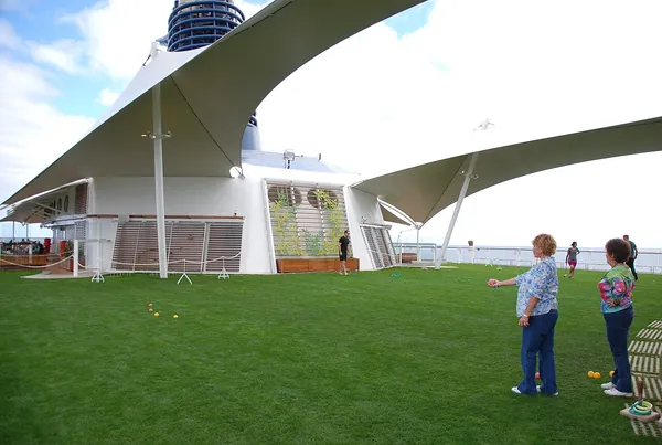 Guests on the real-grass Lawn Club on the top deck of Celebrity Equinox