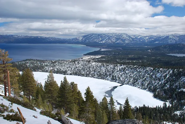 Frozen Cascade Lake and Lake Tahoe beyond, ringed by snowy forest
