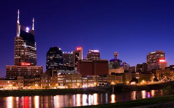 The Nashville skyline lit up at night and reflected in the Cumberland River
