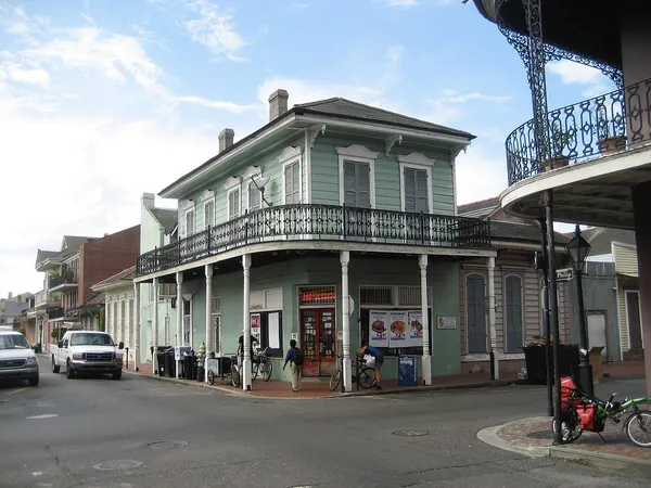 A green historic building with iron balconies on a French Quarter corner