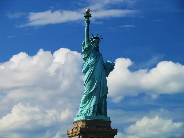 The Statue of Liberty against a blue sky with white clouds