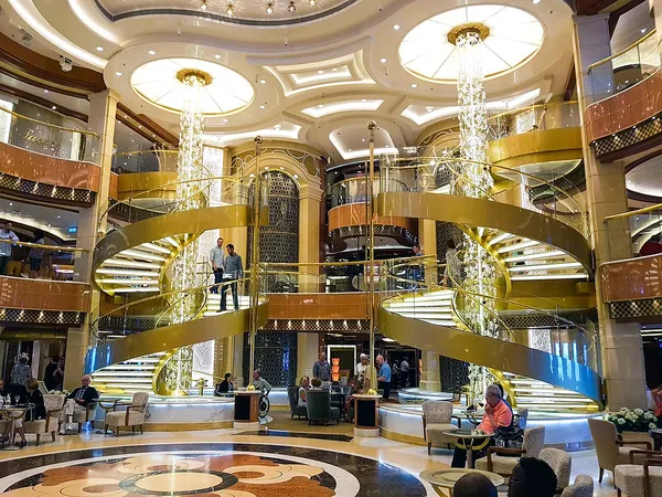 The golden, multi-level Piazza atrium with spiral staircases and chandeliers on Regal Princess