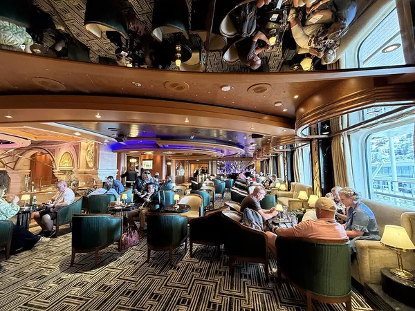 Guests relaxing in Crooners bar with big windows looking out to sea on Ruby Princess