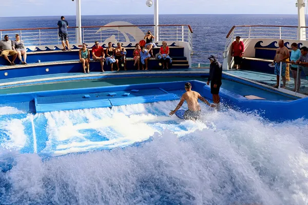 A guest surfing the FlowRider wave simulator on the top deck of Harmony of the Seas