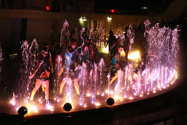 Performers and fountains lit pink and purple during The Fine Line show at the AquaTheater, Harmony of the Seas