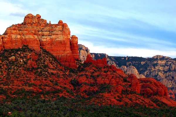 Bright red rock cliffs above green trees in Sedona