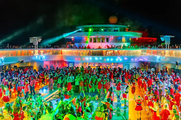 Guests dressed in red partying on the pool deck during Scarlet Night on Valiant Lady