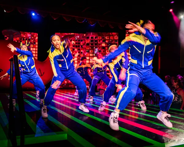 Dancers in blue tracksuits on a lit floor during Untitled Dance Show Party Thing on Valiant Lady