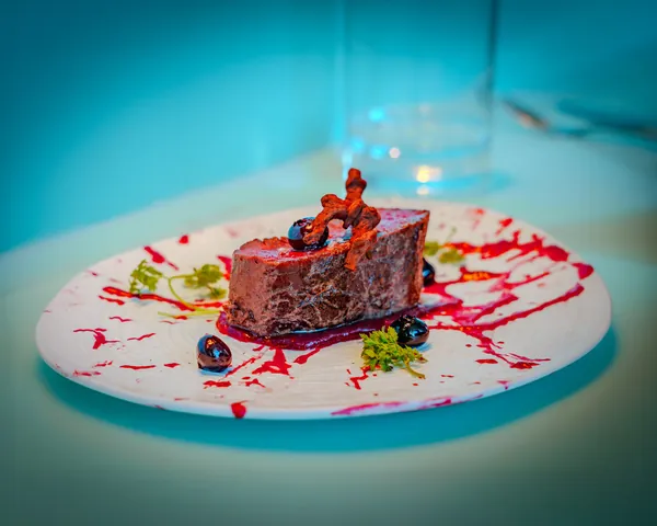 A plated beef dish with red sauce at Test Kitchen on Valiant Lady