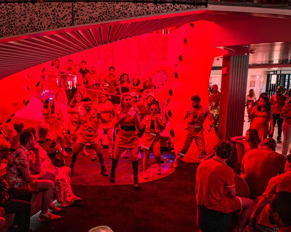 A red-lit crowd watching the Happenings Cast on Scarlet Night aboard Valiant Lady