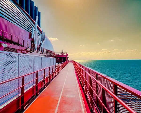 The red-railed outdoor deck of Valiant Lady glowing at sunset