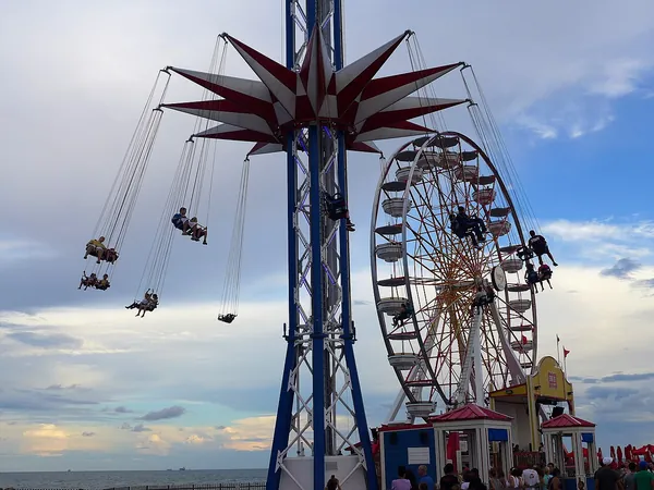 The swing ride and Ferris wheel on the Historic Pleasure Pier against a blue sky