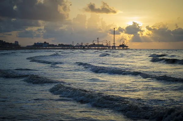 Waves rolling onto Galveston Beach under a golden sunset