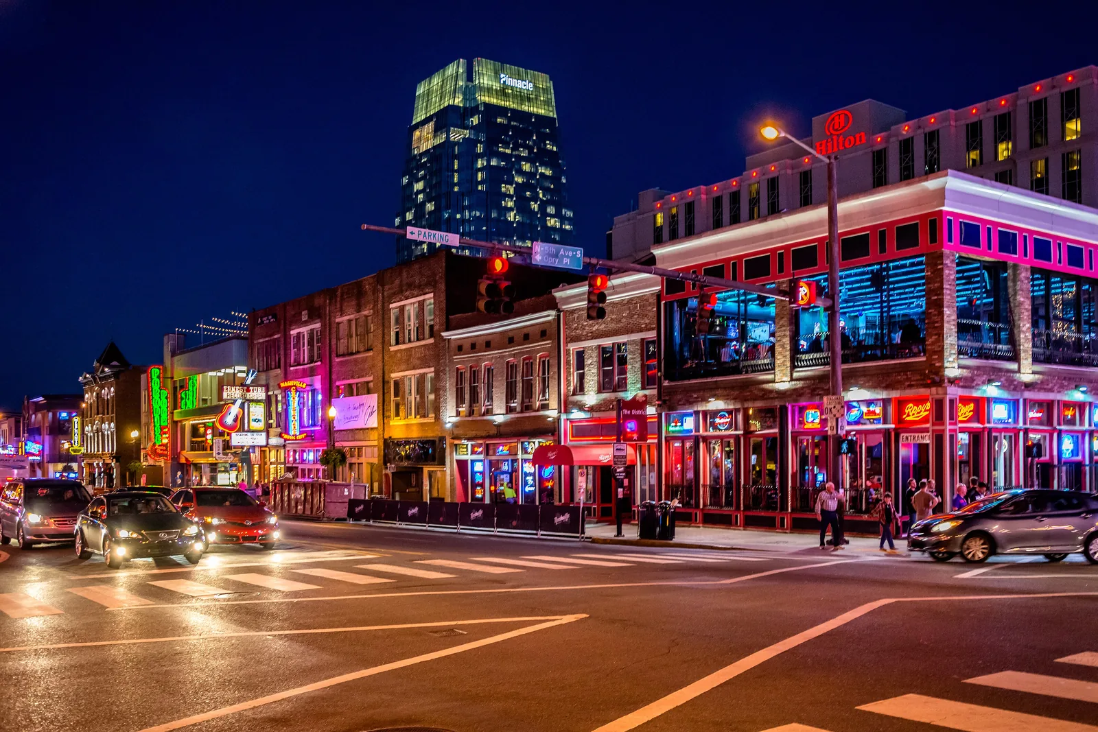 Neon signs of honky-tonks glowing along Lower Broadway at night in Nashville, Tennessee
