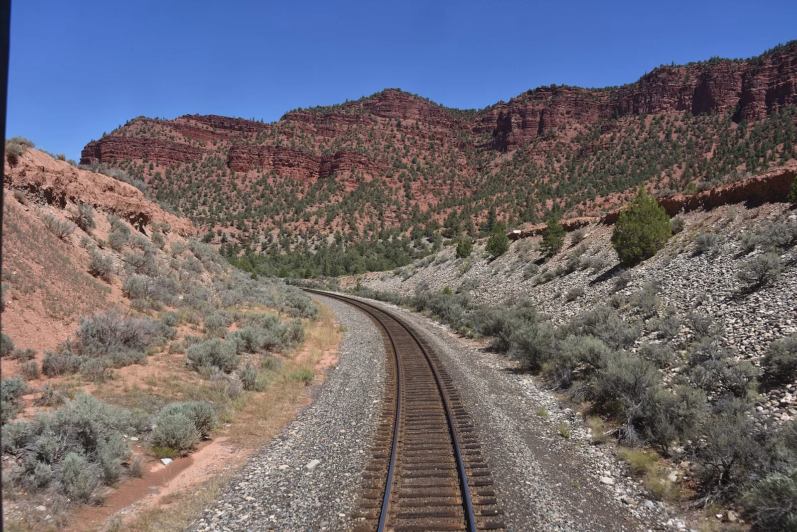 View from the back of an Amtrak California Zephyr train winding through red rock canyon country in Colorado