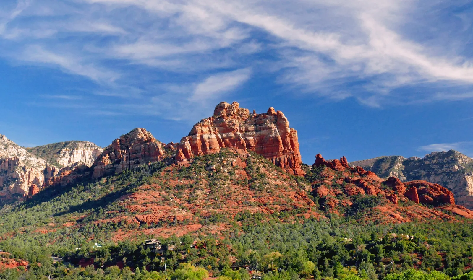 Red rock formations and green desert trees under a blue sky with white clouds in Sedona, Arizona