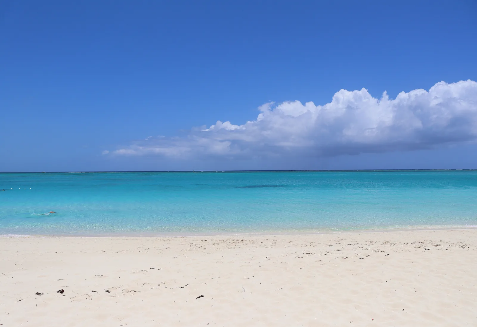 Empty white-sand beach and calm turquoise water under a blue sky at Grace Bay, Providenciales, Turks and Caicos